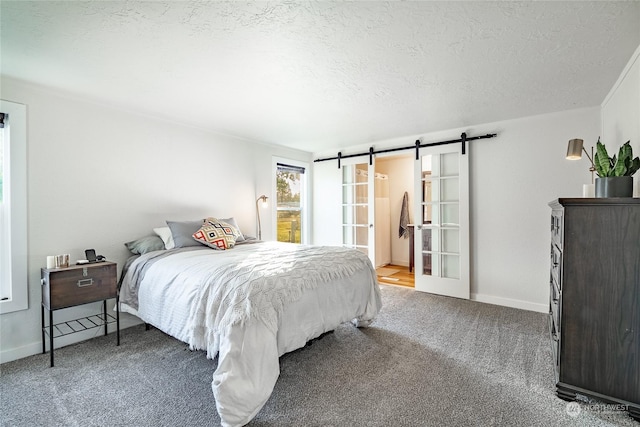 bedroom featuring a barn door, carpet floors, a textured ceiling, and ensuite bath