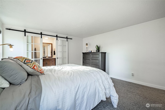 carpeted bedroom featuring a barn door and ensuite bath