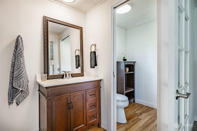 bathroom with vanity, hardwood / wood-style flooring, toilet, and ornamental molding