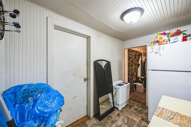 interior space with washer / clothes dryer, wood walls, and white refrigerator