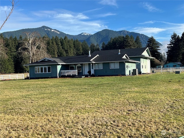 ranch-style home featuring a mountain view, central AC, and a front lawn