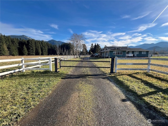 view of gate with a mountain view, a rural view, and a yard