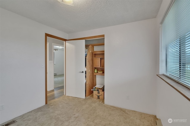 unfurnished bedroom featuring a closet, light colored carpet, and a textured ceiling