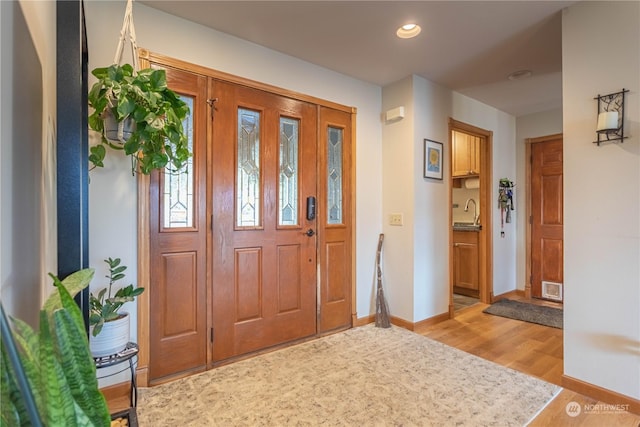 foyer entrance with light wood-type flooring and sink