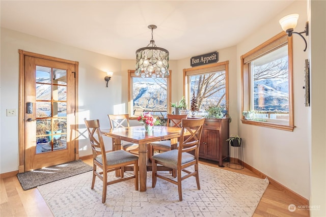 dining space with light hardwood / wood-style floors, plenty of natural light, and a notable chandelier