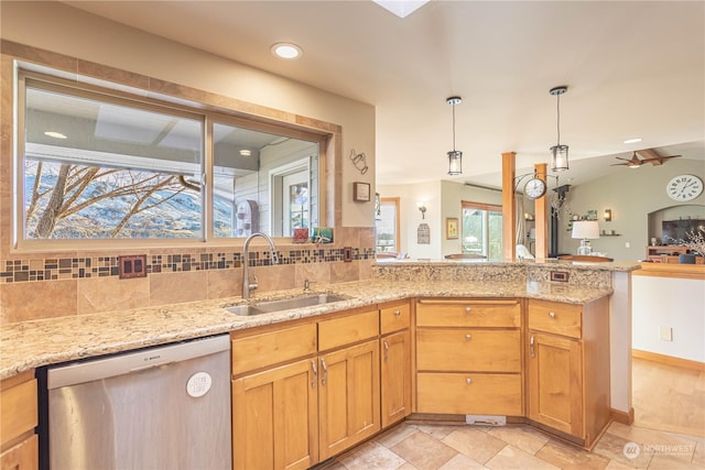 kitchen featuring light stone counters, ceiling fan, sink, decorative light fixtures, and dishwasher