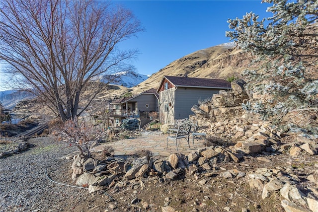 view of property exterior with a deck with mountain view and a patio