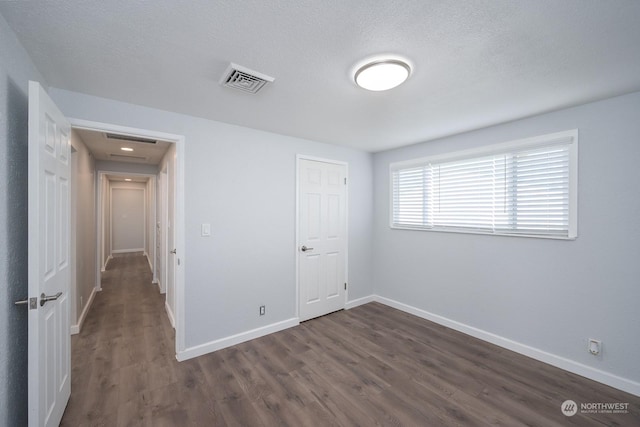 unfurnished bedroom with a textured ceiling, a closet, and dark hardwood / wood-style floors