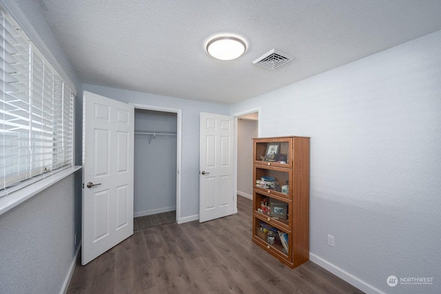 bedroom featuring dark hardwood / wood-style floors, a textured ceiling, and a closet