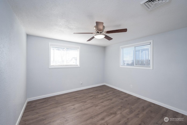 unfurnished room with a textured ceiling, a wealth of natural light, and dark hardwood / wood-style floors