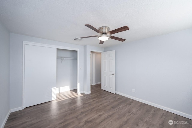 unfurnished bedroom with ceiling fan, dark hardwood / wood-style floors, a textured ceiling, and a closet