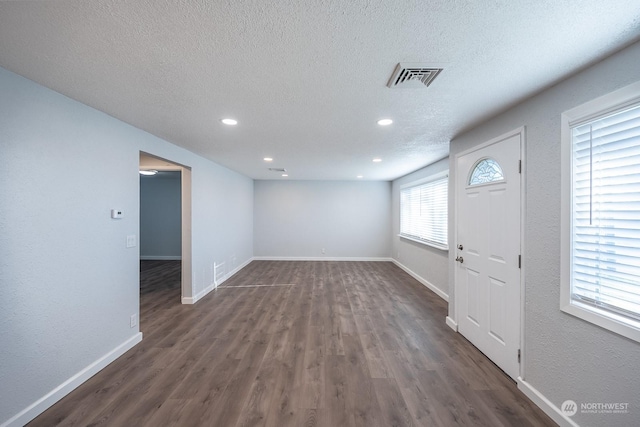 interior space with a textured ceiling and dark hardwood / wood-style floors