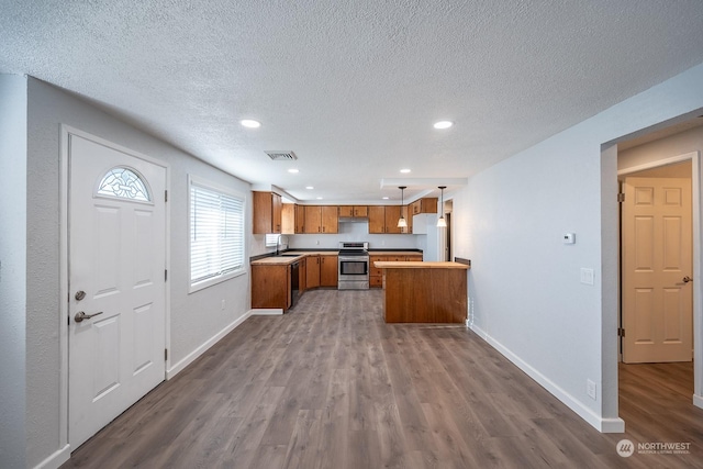 kitchen with pendant lighting, white refrigerator, a textured ceiling, stainless steel range oven, and wood-type flooring