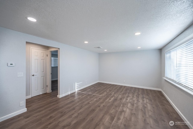 unfurnished room with dark hardwood / wood-style flooring and a textured ceiling