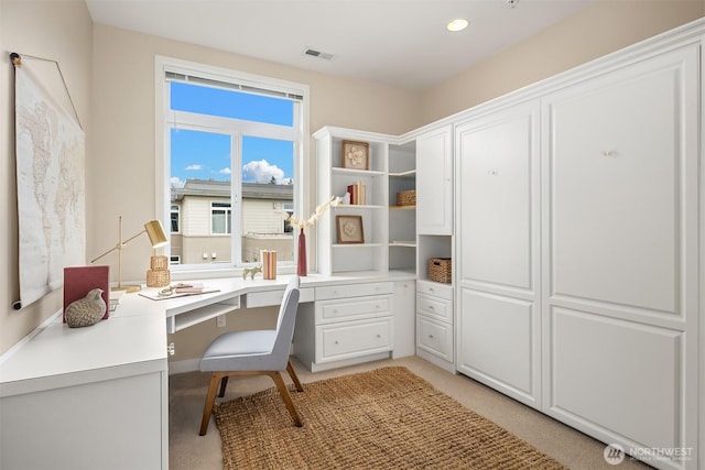 home office featuring visible vents, light colored carpet, and built in study area