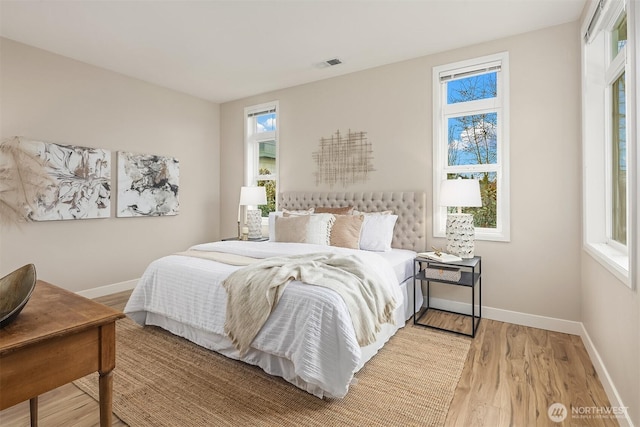 bedroom featuring visible vents, baseboards, and wood finished floors