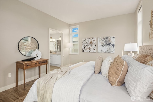 bedroom with a sink, connected bathroom, baseboards, and light wood finished floors