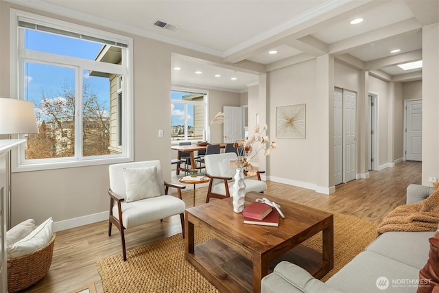 living area featuring visible vents, baseboards, crown molding, and light wood-style floors