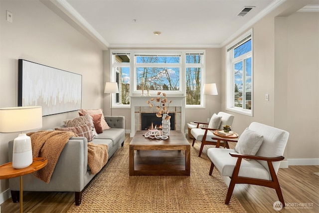 sitting room featuring wood finished floors, visible vents, baseboards, a fireplace, and crown molding