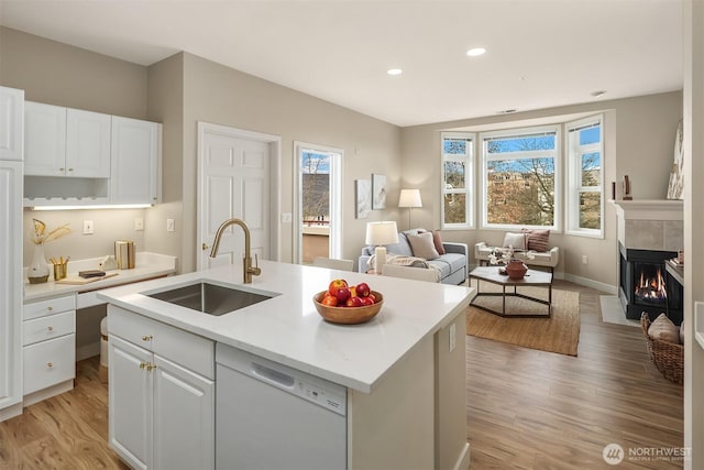 kitchen with light countertops, white cabinets, white dishwasher, and a sink