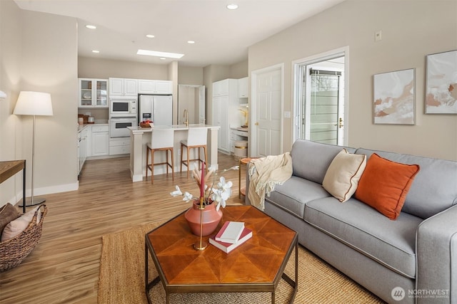 living area featuring recessed lighting, light wood-type flooring, and baseboards