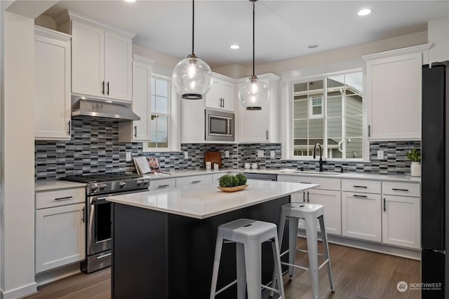 kitchen with decorative backsplash, stainless steel appliances, a center island, dark hardwood / wood-style floors, and white cabinetry