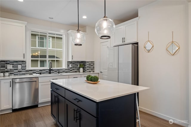 kitchen with backsplash, white cabinets, pendant lighting, and appliances with stainless steel finishes