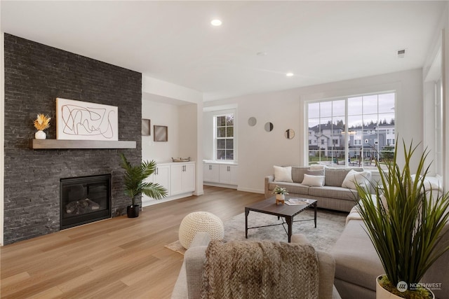 living room with a large fireplace and light hardwood / wood-style flooring