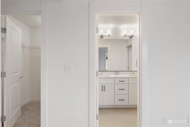 hall featuring sink and light colored carpet