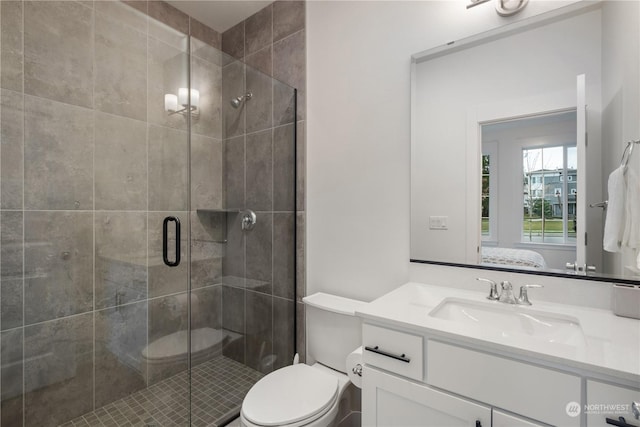 bathroom featuring vanity, toilet, and a shower with door