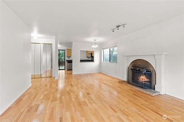 unfurnished living room with a fireplace, track lighting, and light hardwood / wood-style flooring