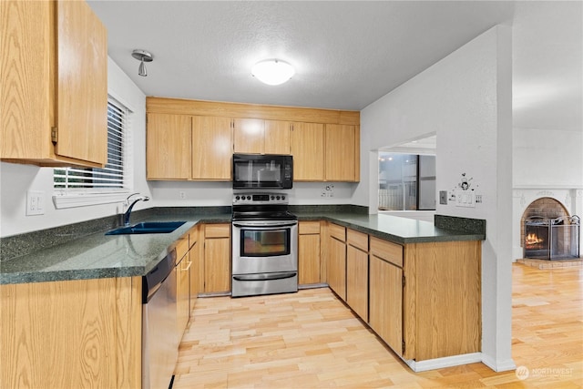 kitchen featuring a textured ceiling, sink, stainless steel appliances, and light hardwood / wood-style flooring