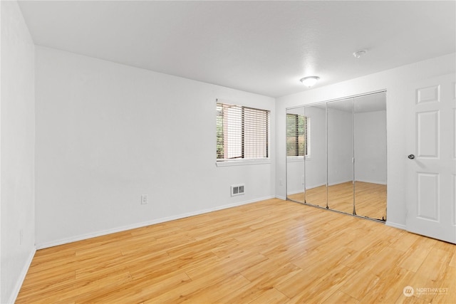 unfurnished bedroom featuring light hardwood / wood-style flooring and a closet