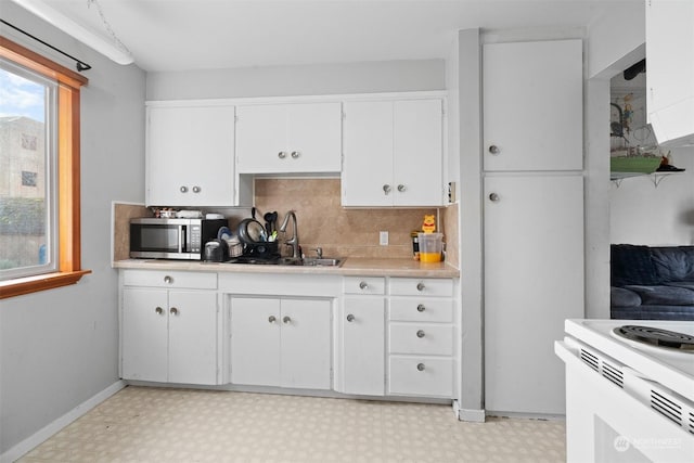 kitchen with decorative backsplash, white cabinetry, sink, and white electric range