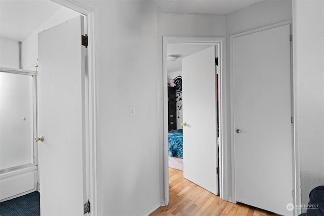 hallway featuring a textured ceiling and light hardwood / wood-style flooring