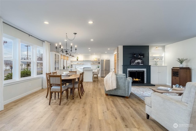 dining area with a fireplace, light hardwood / wood-style floors, a notable chandelier, and sink