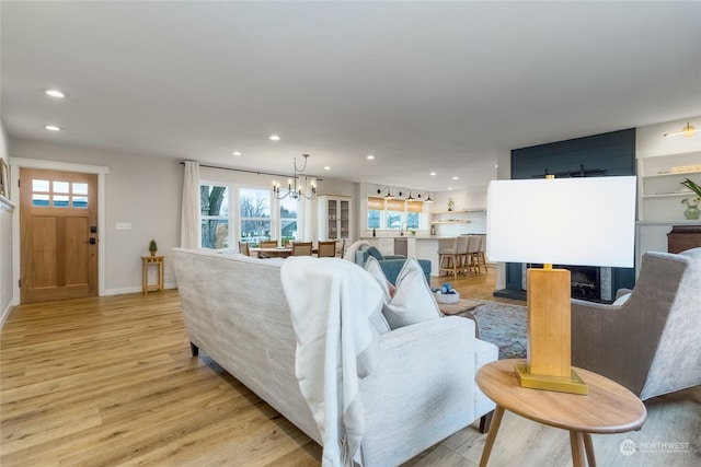 living room with a multi sided fireplace, a wealth of natural light, light hardwood / wood-style floors, and an inviting chandelier