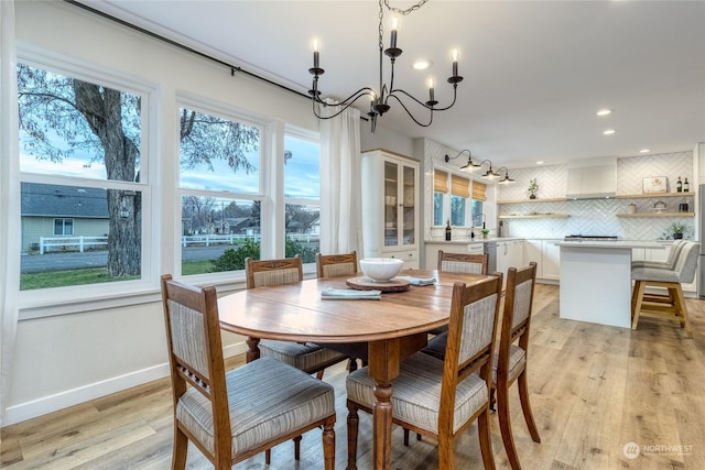 dining room with a notable chandelier, light hardwood / wood-style floors, and a healthy amount of sunlight