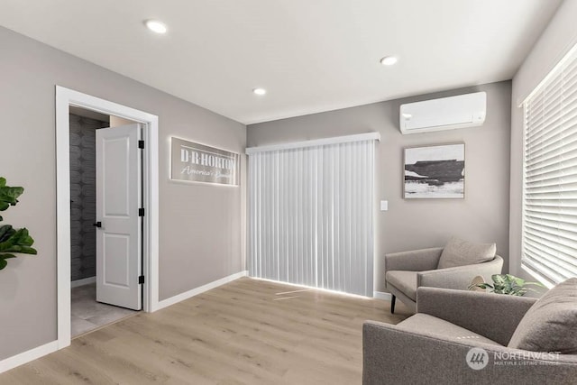 sitting room with a wall mounted air conditioner and light hardwood / wood-style floors