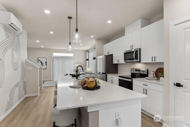 kitchen with appliances with stainless steel finishes, pendant lighting, and an island with sink