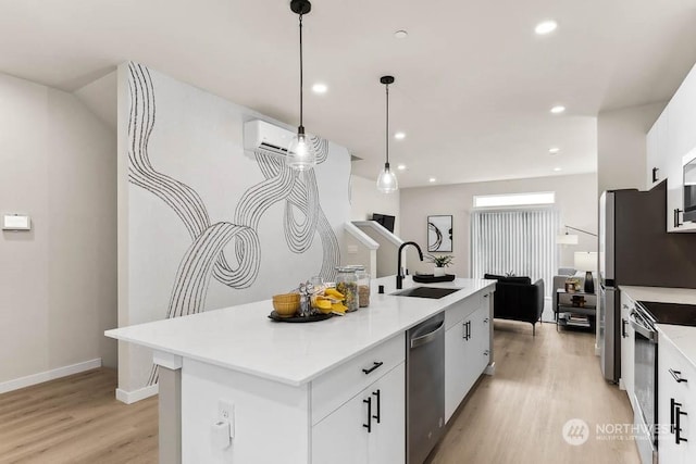 kitchen featuring stainless steel appliances, sink, decorative light fixtures, white cabinets, and an island with sink