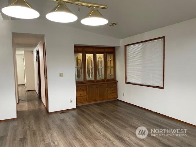 spare room featuring lofted ceiling and dark wood-type flooring