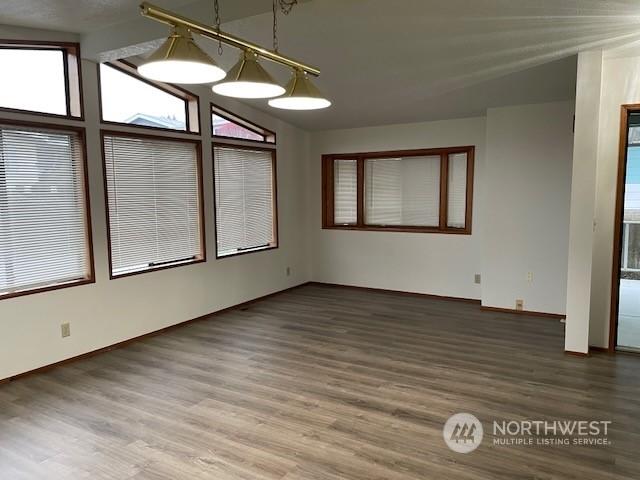 unfurnished dining area featuring lofted ceiling with beams and wood-type flooring