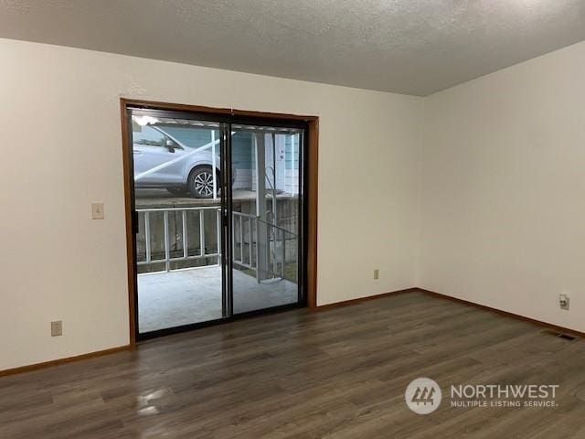 empty room featuring a textured ceiling and dark hardwood / wood-style flooring