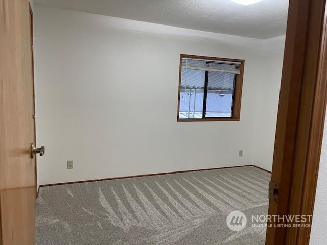 carpeted spare room featuring a textured ceiling