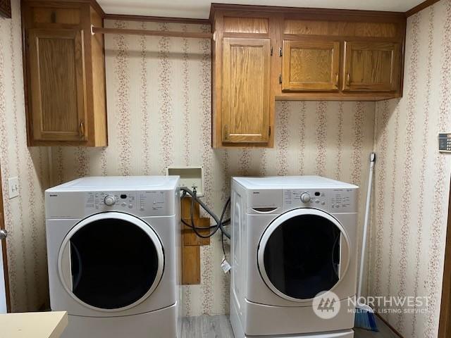 washroom featuring light hardwood / wood-style floors, washer and dryer, cabinets, and ornamental molding