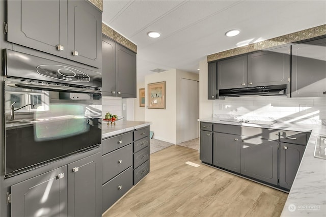 kitchen featuring gray cabinets, decorative backsplash, black appliances, and light hardwood / wood-style floors