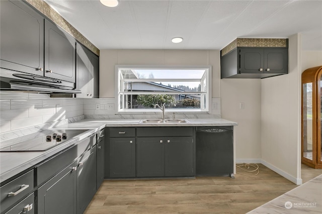 kitchen featuring sink, light hardwood / wood-style flooring, backsplash, gray cabinets, and black appliances