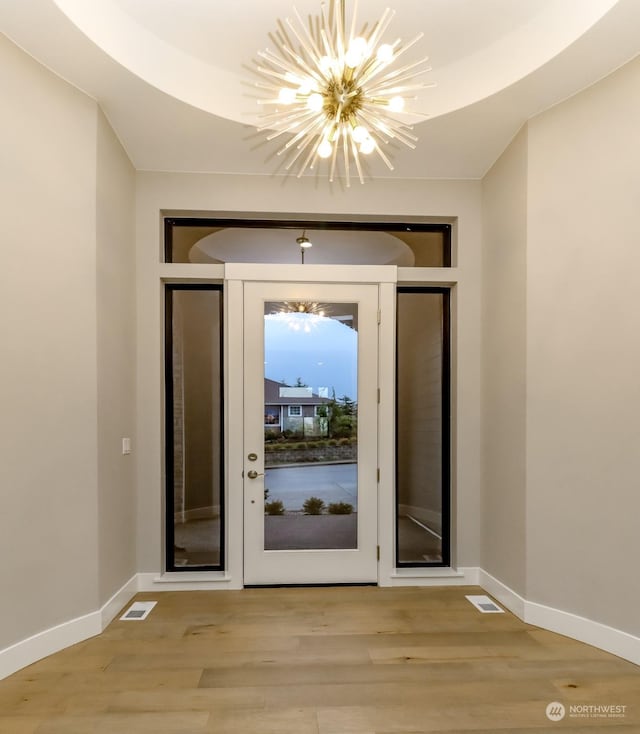 doorway with light hardwood / wood-style floors and a notable chandelier