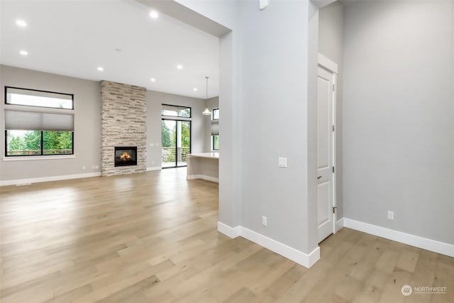 unfurnished living room with a stone fireplace and light wood-type flooring